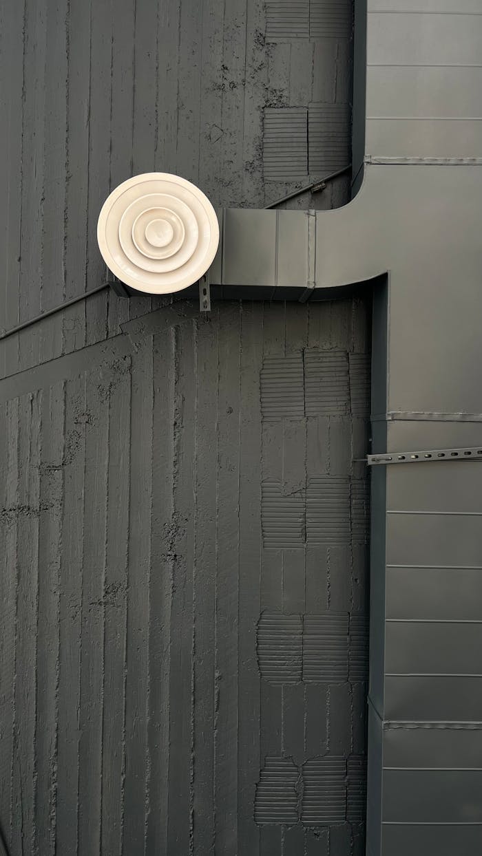 Modern urban exhaust vent against a gray wall in Al Qassim, Saudi Arabia.